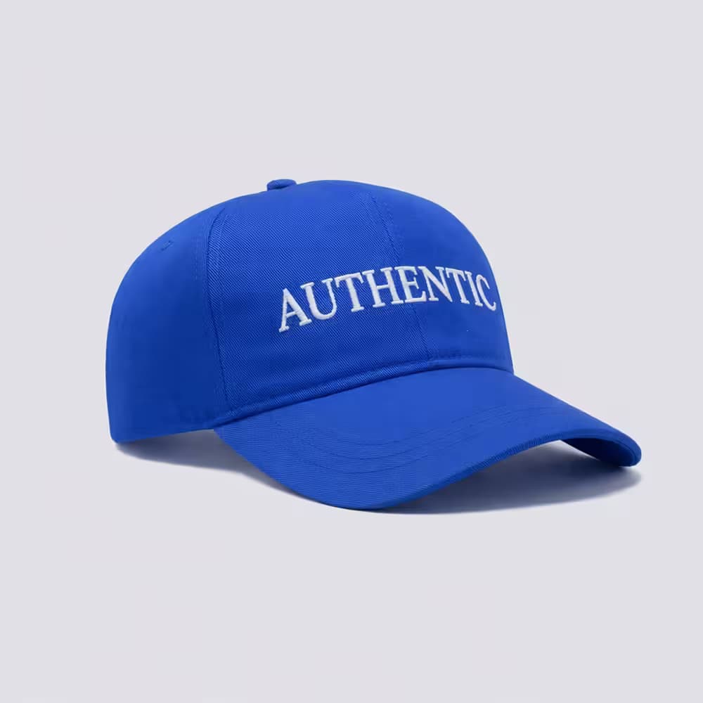 A vibrant blue baseball cap with 'AUTHENTIC' embroidered in white text on the front, set against a plain light grey background.