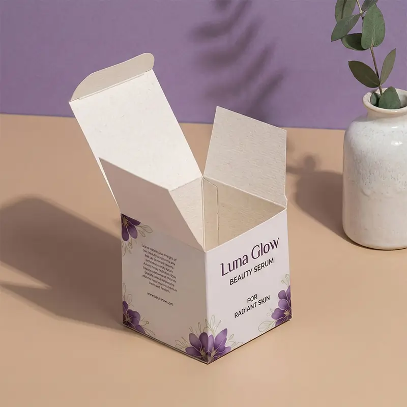 An open "Luna Glow Beauty Serum" box with purple floral accents, displayed next to a white vase and green leaves.