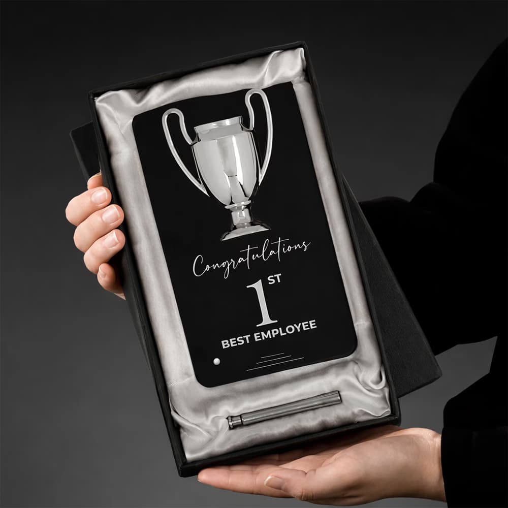 Hands holding a black Winner Cup Desk Trophy with a chrome cup emblem, presented in a luxury satin-lined box for the 1st Best Employee.