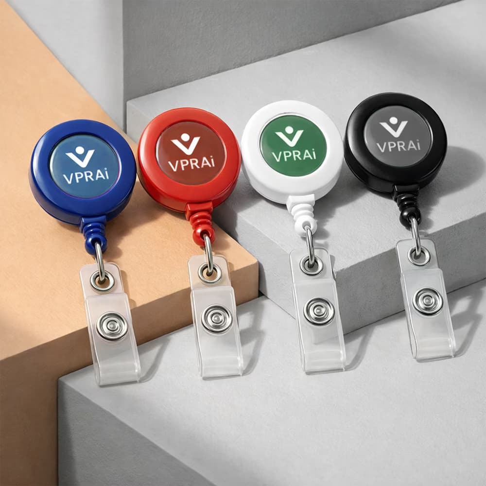 Four retractable ID card holders in blue, red, white, and black with logo branding and clear vinyl badge clips.