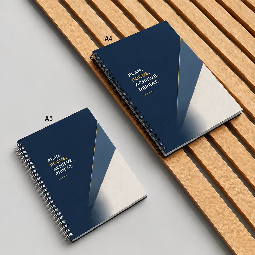 Two navy geometric wiro notebooks comparison guide, labeled as A4 and A5 sizes, resting on wooden slats.