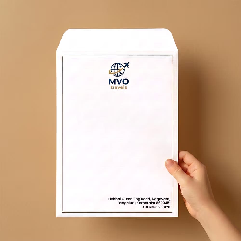 Custom corporate envelope mockup for MVO Travels held by hand, featuring a printed logo, company address, and phone number.