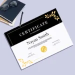 Black and white certificate for Nayan Smith with gold floral corners, pictured on a desk with a notebook.
