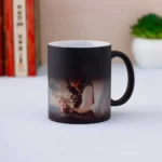 A Quapri Personalized Color-Changing Magic Mug sits on a cozy living room table next to a plate of cookies. The mug displays a vibrant design as it’s filled with steaming tea.