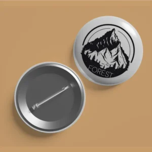Front and back view of a white button badge with a black mountain logo and the word "FOREST.