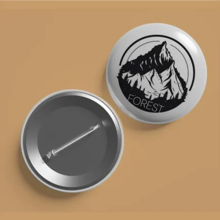 Front and back view of a white button badge with a black mountain logo and the word "FOREST.