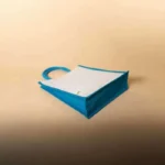 Flat lay of a white jute bag with bright blue gussets and handles on a tan background.