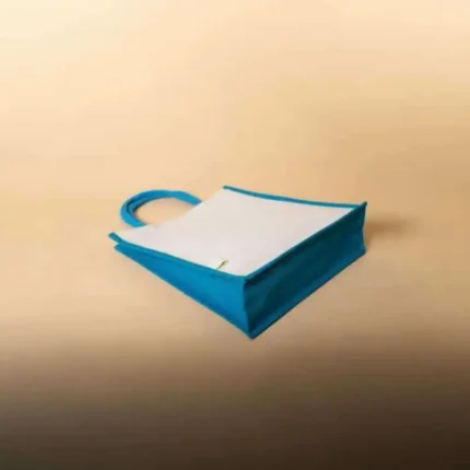 Flat lay of a white jute bag with bright blue gussets and handles on a tan background.