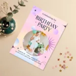 A pink and purple celestial first birthday invitation featuring a baby's photo, stars, and modern graphics.
