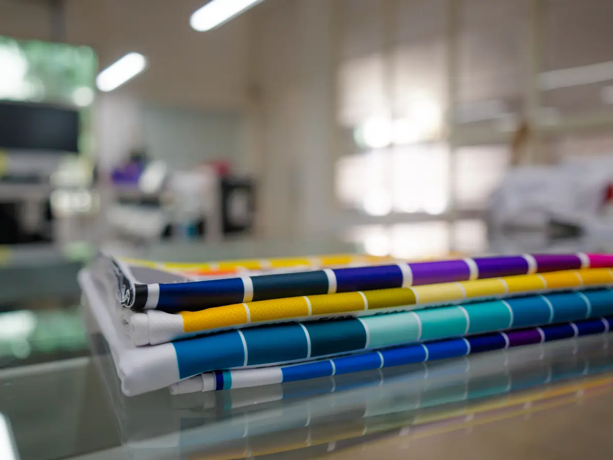 Colorful printed fabric banners stacked on a glass surface in a printing workshop, ideal for custom banner printing