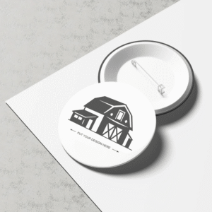 Round white Custom Button Badges with a barn illustration and safety pin back, placed on a light surface.
