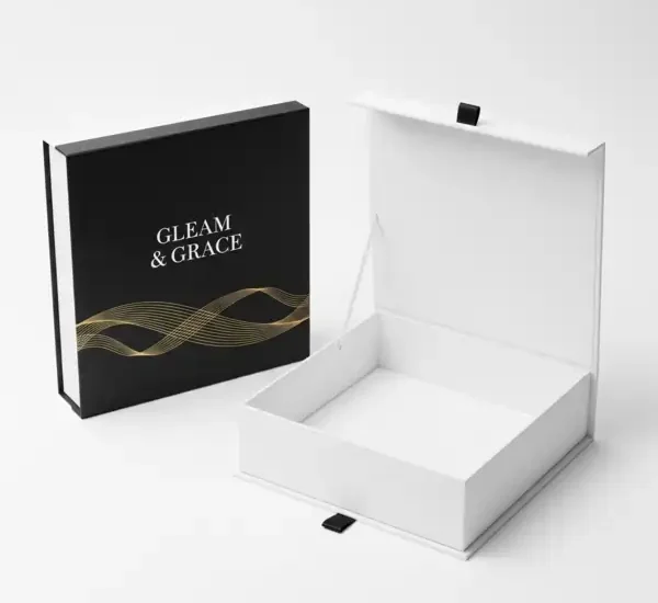 A two-part gift box with a black lid featuring a gold wave pattern and 'GLEAM & GRACE' text, paired with a white base, is perfect for Packaging Boxes Printing.