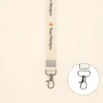 Cream-colored custom lanyard with side lever hook, printed “Your Designs,” small orange icon, and metal clasp for ID cards or keys.