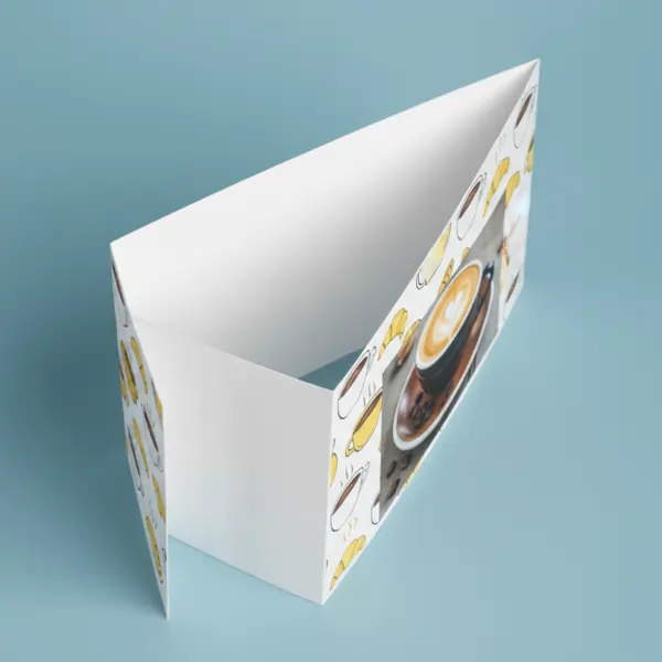 Tent Cards Printing: A folded white tent card featuring a design with small illustrations of coffee cups and croissants, and a photo of a coffee with latte art.
