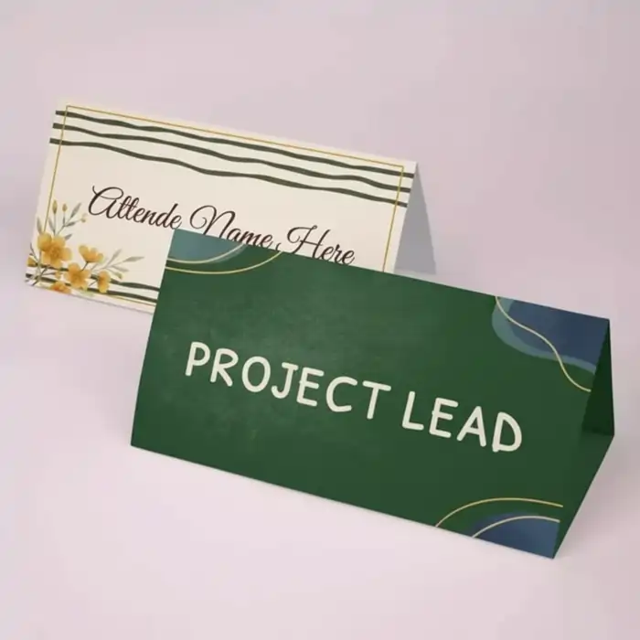 Tent Cards Printing: Two horizontal tent cards shown; one dark green with "PROJECT LEAD" and one cream-colored for "Attendee Name Here" with floral design.