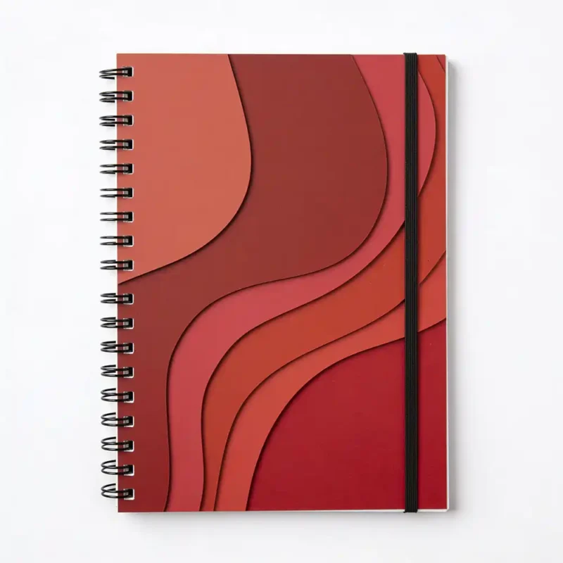 Top-down view of a red wiro notebook with wavy, layered paper-cut art on the cover and a black elastic closure band.