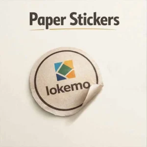 Paper stickers with a simple printed logo design, shown as a round label being peeled from a surface, highlighting texture and matte finish.